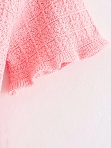 Macro shot of pink knit fabric texture with detailed crochet pattern and soft yarn weave
