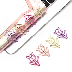 Detailed view of colorful tulip-shaped metal paperclips on a pink notebook and desk