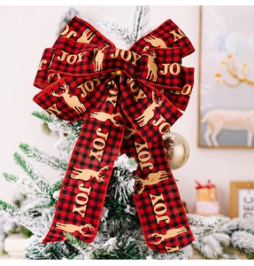 Detail of red and black plaid Christmas bow with golden JOY and reindeer on a tree
