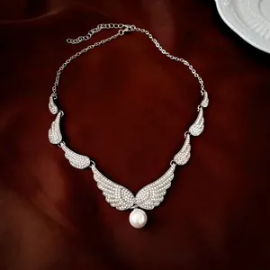 Close-up of luxury angel wing necklace with silver rhinestones and a white pearl drop