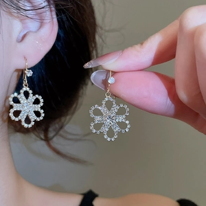 Close-up of elegant gold flower earrings with sparkling crystals worn by a model