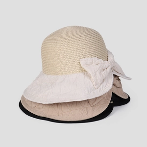 Detail of stacked summer straw hats featuring bow decoration and pleated fabric brims