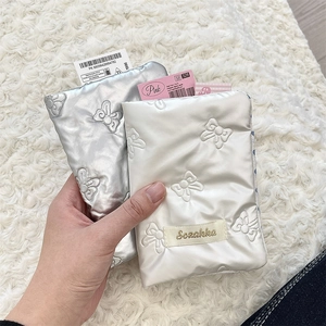 Close-up of quilted PU bow passport holders in silver and white with satin finish