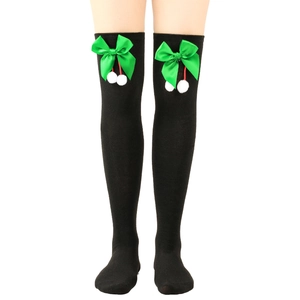 Detail of black over-knee Christmas socks with green satin bow and white pom-poms