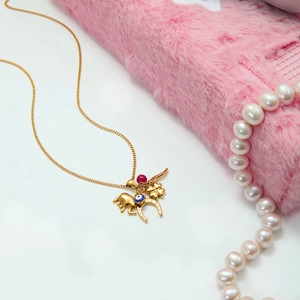 Detail of 18K gold horseshoe and evil eye charms on a delicate O-chain necklace