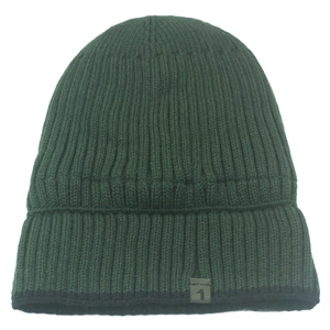 Detail of dark green ribbed knit beanie with small numeric woven label and thick texture