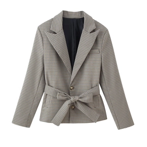 Detail of brown plaid blazer featuring textured fabric, notched lapels and matching waist belt