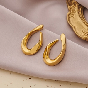 Boucles d'oreilles dorées irrégulières en forme de U sur velours rose