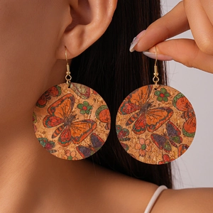 Detail of round cork earrings with colorful butterfly pattern and golden metal hooks