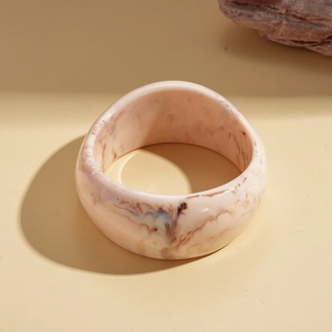 Macro detail of wide resin bangle featuring pink marble texture and polished finish