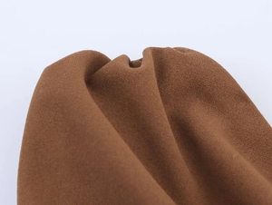 Vue macro du tissu froissé marron montrant le drapé et les détails du haut asymétrique