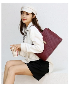 Détail de la texture tressée bordeaux et de la boucle en métal doré sur le sac à main