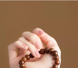 Macro detail of natural golden Phoebe wood prayer beads with smooth grain texture held in hand