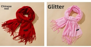 Detail of red and bright pink cashmere scarves featuring fringe edges and woven labels