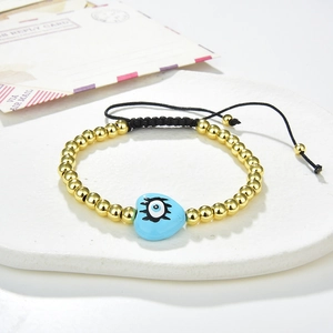 Detailed shot of an adjustable evil eye bracelet with golden beads and blue heart charm