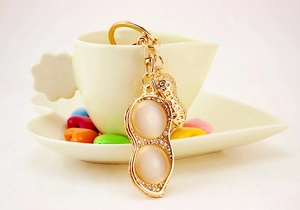 Detail of a golden peanut keychain with sparkling rhinestones and cat eye opal stones