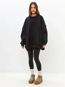 Oversized black crewneck sweatshirt with leggings and beige snow boots for a chic winter look