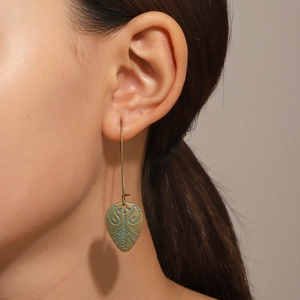 Gros plan de boucles d'oreilles feuilles en bronze avec émail ethnique bleu et vert