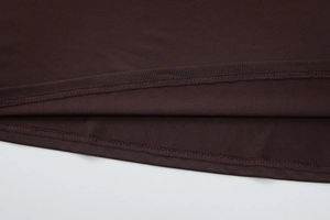 Détail de l'ourlet à double surpiqûre sur une robe en maille marron foncé de qualité