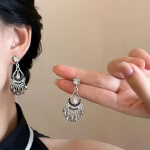 Close-up of bohemian silver drop earrings with grey crystal tassels on a female model