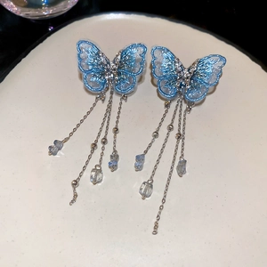 Close-up of blue embroidered butterfly earrings with silver tassels and crystal beads