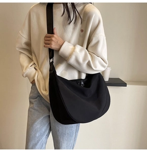 Detail of a large black waterproof Oxford crossbody bag worn in a casual lifestyle setting