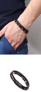 Detail of tiger eye beads and braided leather cord with magnetic metal clasp on a men bracelet