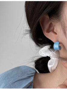 Close-up of a minimalist light blue C-shaped resin earring on model ear for summer