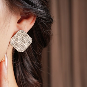 Close-up of model wearing square silver hoop earrings with shimmering crystal pavé