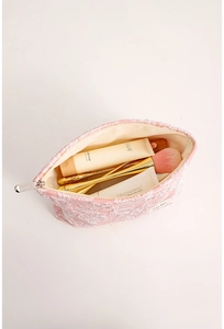 Pink embossed makeup bag with large capacity showing interior storage for brushes