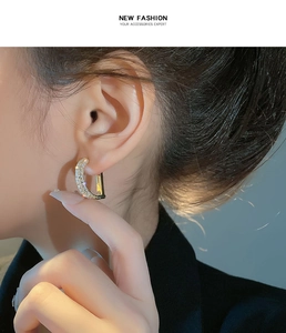 Detailed close-up of a gold D-shaped earring with shimmering pave-set cubic zirconia crystals