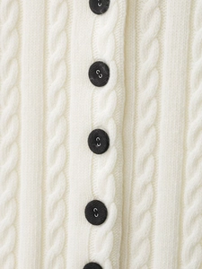 Macro view of cable knit pattern with matte black buttons on a beige cardigan