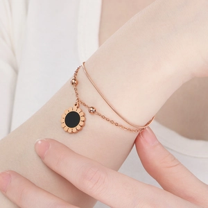 Détail du bracelet double couche en or rose avec breloque tournesol en opale noire au poignet