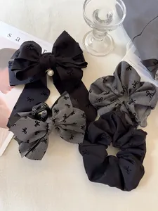 Dettaglio di fermagli per capelli a fiocco e elastici in grigio e nero con perla