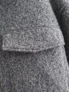 Macro view of grey bouclé texture jacket showing pocket flap and stitching details