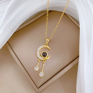 Gold moon pendant necklace with tassel, encrusted with crystals and dark center stone