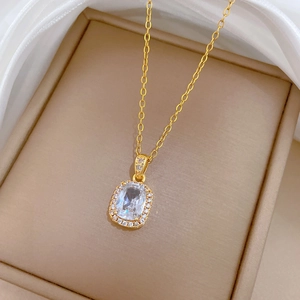 Luxurious gold necklace with rectangle cubic zirconia pendant shown on silk background