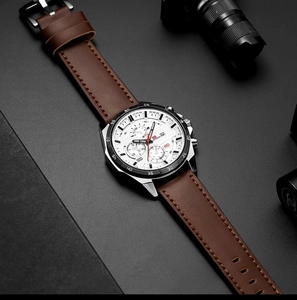 Macro detail of silver steel case and white chronograph dial with brown leather strap