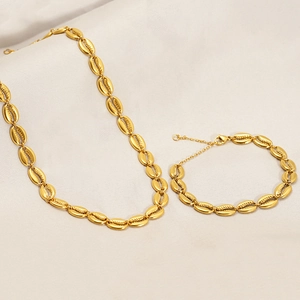 Détail du collier pendentif coquillage doré et du bracelet assorti sur un tissu
