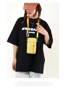 Detail of bright yellow crossbody phone bag with heart zipper and adjustable strap