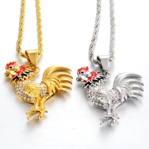 Detailed view of rooster pendants in gold and silver with white rhinestones and enamel work