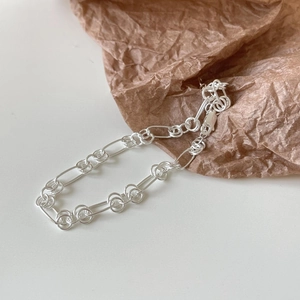 Detailed view of 925 sterling silver O-ring chain bracelet on a textured background