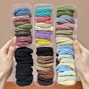 Détails d'élastiques à cheveux spirale colorés rangés dans des boîtes en plastique clair