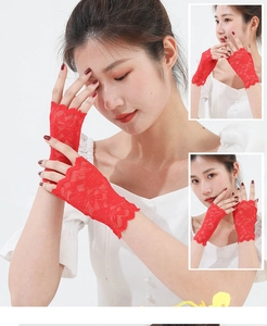Macro detail of red lace fingerless gloves with floral embroidery and scalloped edges