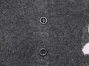 Vue détaillée du tissu en laine gris foncé et des boutons en résine sur le cardigan