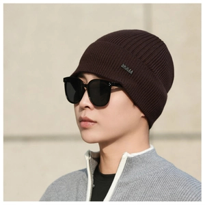 Detail of dark brown ribbed knit beanie featuring a small silver rectangular metal logo