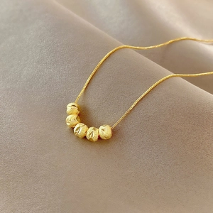 Macro shot of gold transfer bead necklace with five faceted beads on champagne silk