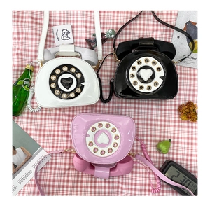 Detailed flat lay of retro telephone bags in white, black, and pink with patent leather