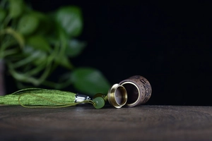 Detail of carved green sandalwood sachet pendant with brass cap and green silk tassel