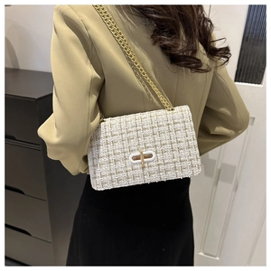 Detail of white tweed crossbody bag with gold chain and metal lock worn by a model